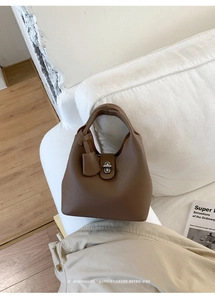Close-up of brown litchi pattern leather bucket bag with silver twist lock and handle