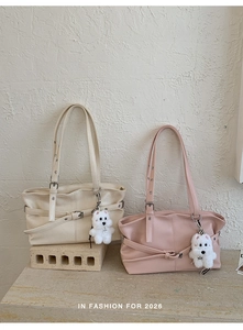 Detail of beige and pink tote bags with decorative straps and plush dog charms
