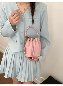 Close-up of pink bucket bag with drawstring and lychee pattern leather texture