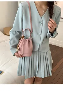 Detail of pink lychee leather bucket bag with drawstring closure and shoulder strap