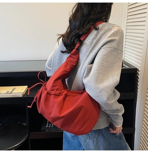 Red nylon crescent bag worn by model showing its large capacity and casual drape style