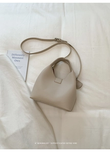 Close-up of beige lychee grain leather bucket bag with adjustable strap and metal buckle