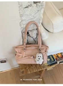 Detail of light pink leather tote bag with criss-cross straps and plush puppy charm