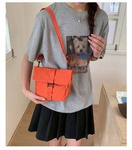Détail du sac bandoulière orange étanche avec boucle de fermeture et texture en maille