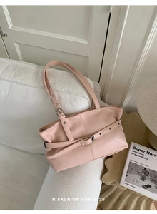 Detailed view of light pink leather tote bag with pleated texture on white sofa
