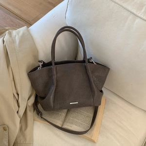 Détail du sac cabas marron vintage avec texture en cuir froissé sur un canapé blanc