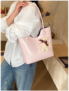 Detail view of pink leather tote bag with a cute teddy bear charm on the shoulder strap