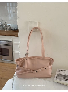 Detail of light pink PU leather tote featuring crossover straps and metallic buckle