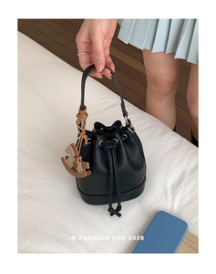 Detail of black pebbled leather bucket bag with drawstring and silver hardware