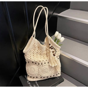 Detail of crochet tote bag with wooden beads tassel on a black background with flowers