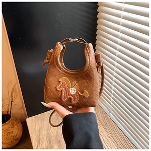 Close-up of brown quilted dumpling bag with cute knitted horse motif and smooth PU leather finish