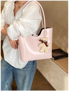Detail of pink glossy patent leather tote bag featuring a cute white teddy bear charm