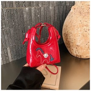 Detail of red mini quilted dumpling bag with horse embroidery held by a model