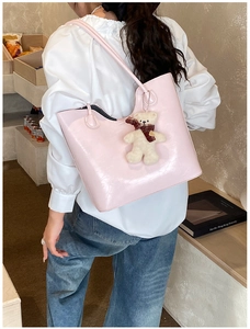 Pink glossy tote bag with cute teddy bear charm showing shoulder carry style and texture