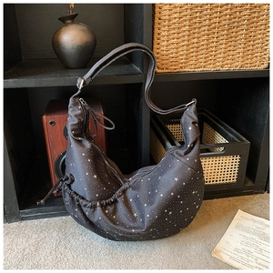Close-up of black crescent hobo bag with white star pattern and adjustable strap