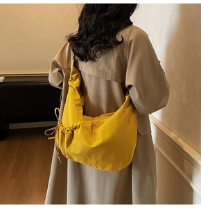 Detailed view of yellow dumpling bag showing the side drawstring bow and nylon texture