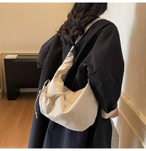 Detail of minimalist oversized crossbody dumpling bag showing drawstring texture and strap