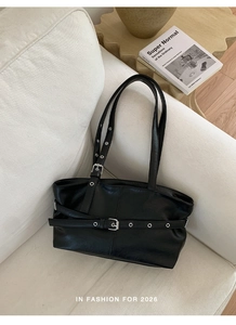 Detailed view of black faux leather tote with silver metal eyelets on a white sofa