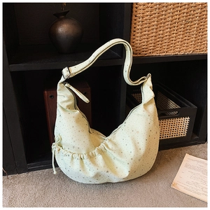 Detailed view of mint green crescent bag with gold star patterns and adjustable strap