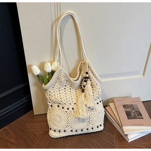 Detail of crochet cotton tote bag with dark wooden beads, tassels and hollow patterns