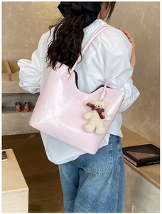 Detail of light pink faux leather tote bag with cute plush bear charm on a shoulder strap