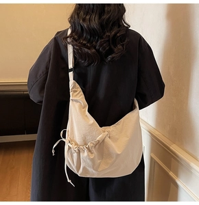 Detail view of the drawstring bow knot on a large beige minimalist crescent crossbody bag