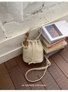 Close-up of beige drawstring bucket bag with lychee grain leather and pony charm