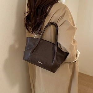 Détail du sac cabas vintage en cuir marron texturé avec plaque métal et bandoulière