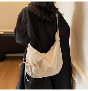 Detail view of the drawstring side ties on a beige minimalist large capacity hobo bag