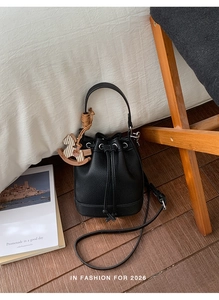 Detail of black pebbled leather bucket bag with drawstring and wooden horse charm