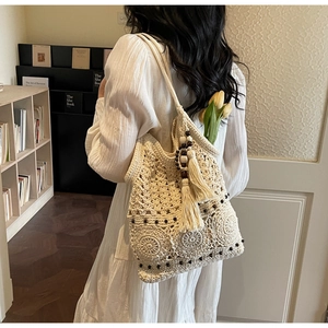 Detail of crochet tote bag featuring wooden beads and tassels in a lifestyle setting