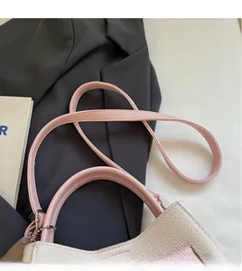 Detail view of pink and beige bucket bag featuring litchi texture and long shoulder strap
