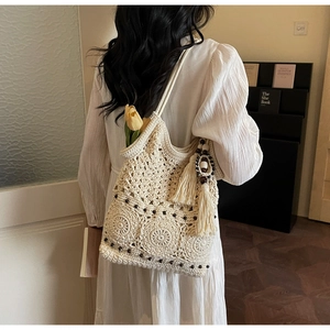 Detail of bohemian ivory crochet shoulder bag with wooden beads and tassels on a model