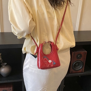 Detail of red quilted dumpling bag with cute pony patch worn by a model in a casual outfit