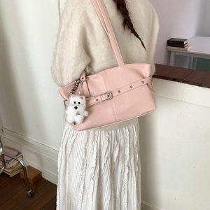 Detail of light pink faux leather tote bag with buckle and white plush dog charm