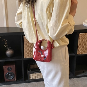 Detail of red quilted mini crossbody bag with colorful horse embroidery decoration