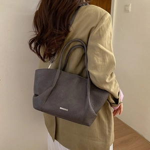 Détail d'un sac cabas en cuir gris foncé avec grainage litchi et plaque métallique