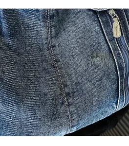 Macro shot of dark blue denim tote bag material with textured twill and silver metal zipper