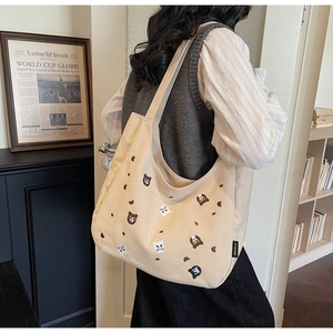 Detailed embroidery of cat and bear patterns on a large beige canvas tote bag