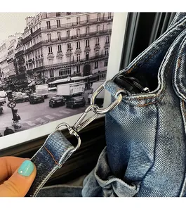 Close-up of silver metal clasp on blue denim tote bag with yellow contrast stitching