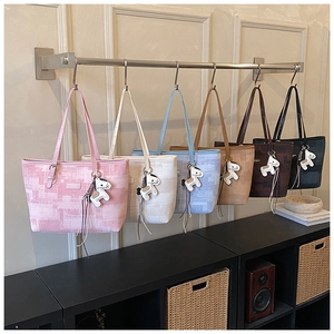 Detail showing various colors of large tote bags with horse charms on display rack