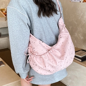 Detail of pink crescent bag showing silver star prints and side drawstring bow decoration