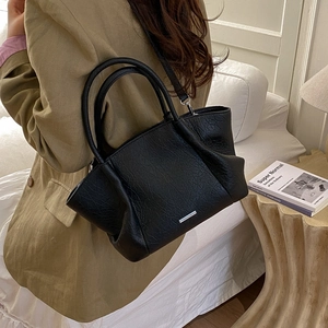 Détail du sac cabas plissé noir montrant le grain texturé et la barre métallique argentée