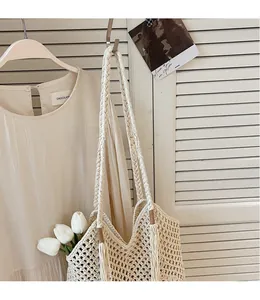 Close-up of beige crochet woven tote bag with long shoulder straps and fringe detail