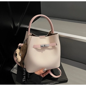 Detail view of cream pebble leather bucket bag with pink handles and silver metal swivel lock