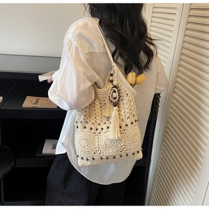 Detailed close-up of crochet shoulder bag with wood beads and decorative cotton tassels