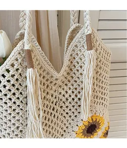 Close-up of beige woven tote bag with yellow sunflower embroidery and tassel detail