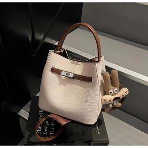 Detail of lychee textured leather bucket bag with metal twist lock and rabbit charm