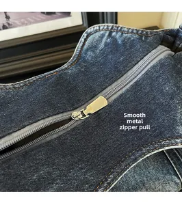 Detailed close-up of smooth silver metal zipper on vintage blue denim tote bag