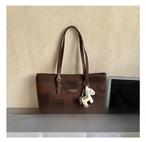 Detail view of large brown tote bag with contrast pattern and decorative pony charm